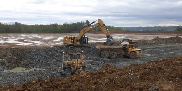 Machines moving dirt and putting it into back of truck