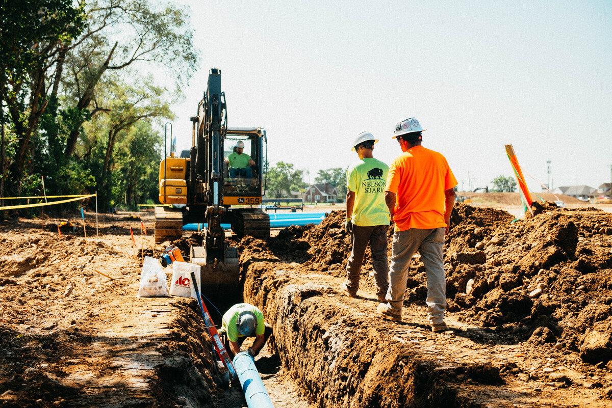 Construction workers installing underground utility pipes